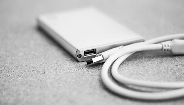 Czarno-białe zdjęcie zewnętrznego dysku z podłączonym kablem USB