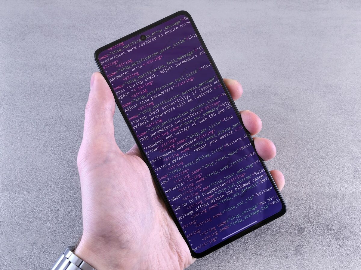 Dłoń trzymająca smartfon z kodem na ekranie